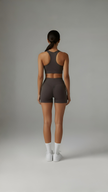 AIRE Sculpt+ Scrunch-Bum Shorts in brown, showing the high-waisted design and textured fabric for sculpting and contouring.