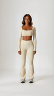 Woman wearing beige long sleeve crop top and high waist flared leggings, athleisure set
