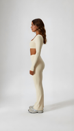 Woman in beige long sleeve crop top and flared leggings, side view, athleisure outfit