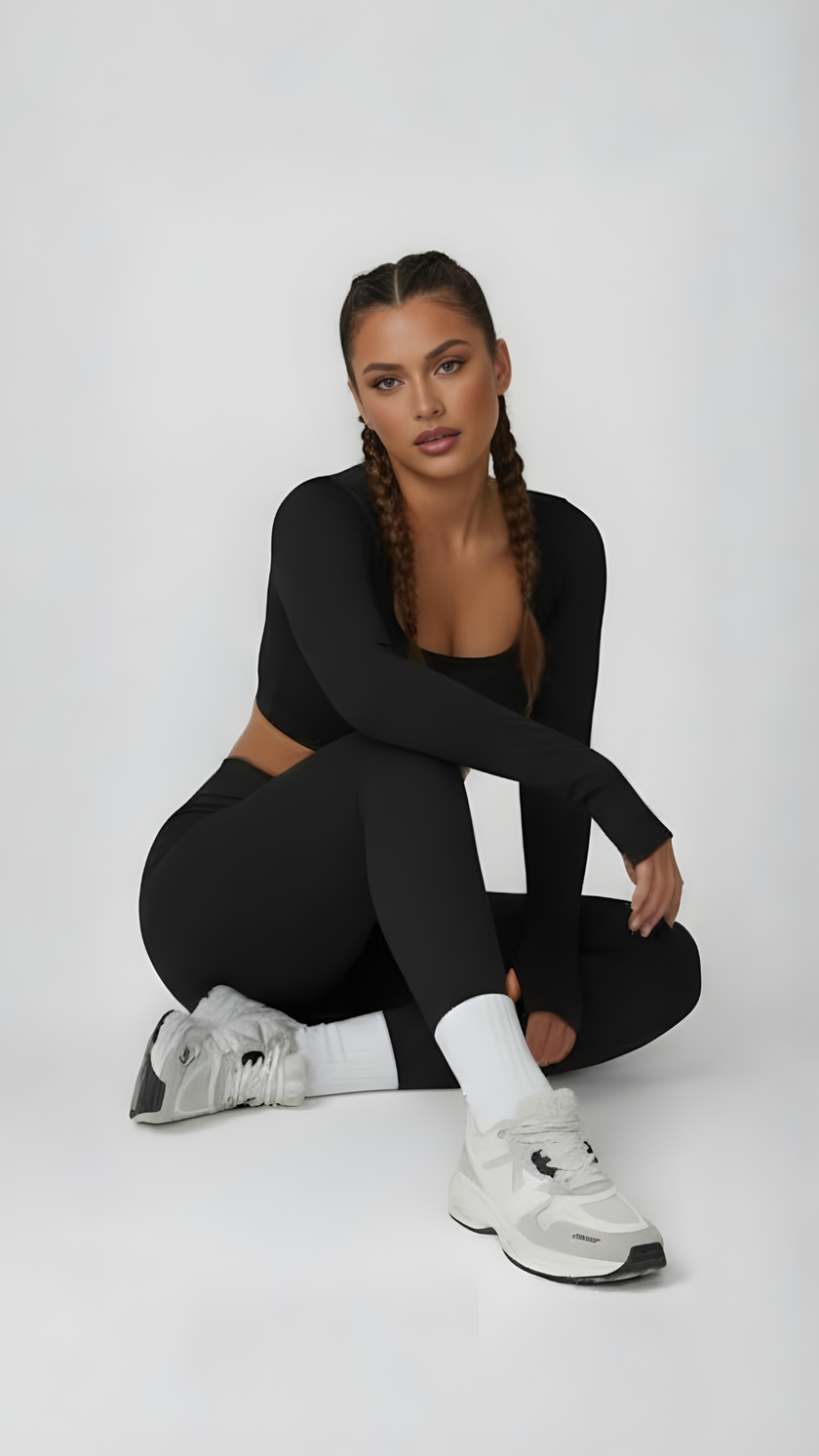 Woman in black long sleeve athleisure top and leggings, styled with sneakers and braids