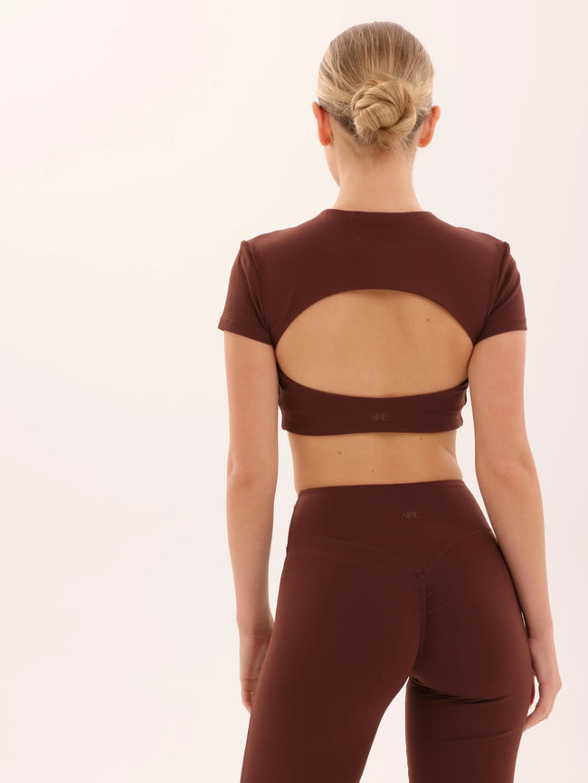 Woman wearing brown seamless activewear set with open-back crop top and high-waisted leggings