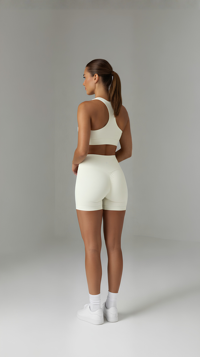 A pair of beige Sculpt+ Scrunch-Bum Shorts by AIRE featuring seamless design and a scrunch detail on the back.