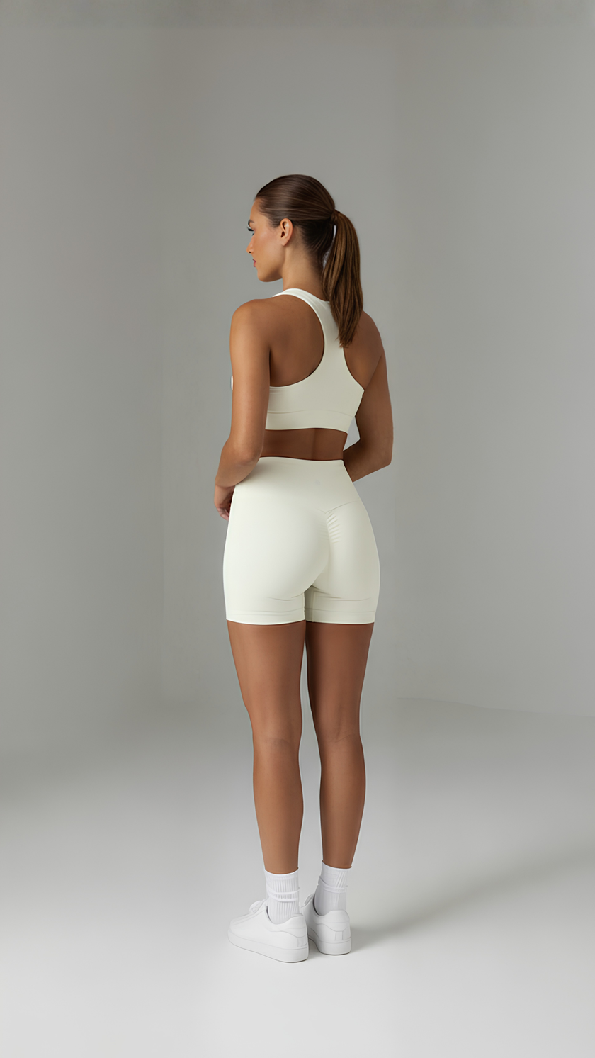 A pair of beige Sculpt+ Scrunch-Bum Shorts by AIRE featuring seamless design and a scrunch detail on the back.